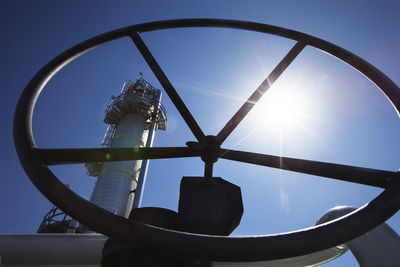 Low angle view of wheel and chimney during sunny day