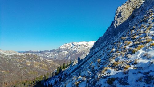 Scenic view of snowcapped mountains against clear blue sky