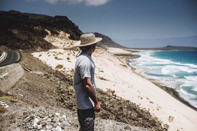 Side view of man standing at beach during sunny day