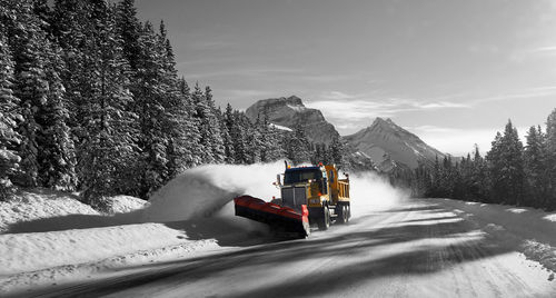 Snow on road by snowcapped mountain against sky