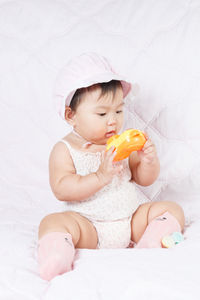 Cute baby girl sitting on bed at home