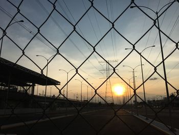 Silhouette fence against sky during sunset