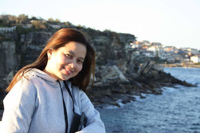 Portrait of smiling mature woman by sea against clear sky