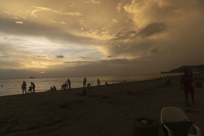 People on beach against sky during sunset