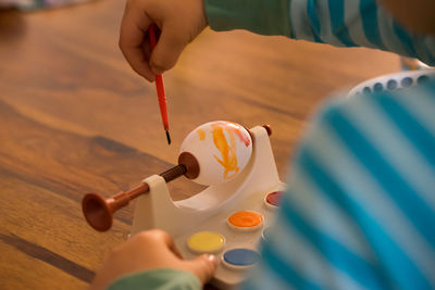 Midsection of boy painting egg during easter