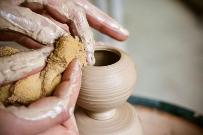 Girl sculpts in clay pot closeup. modeling clay close-up. caucasian man making vessel daytime 