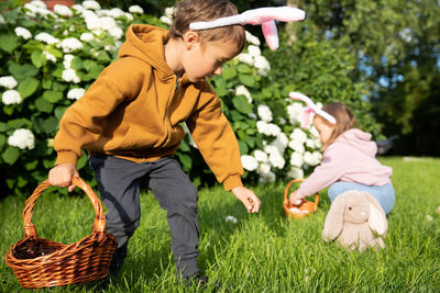 Side view of boy playing with teddy bear on field