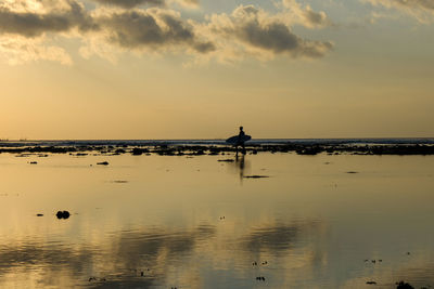 A surfer at sunset. bali, indonesia.