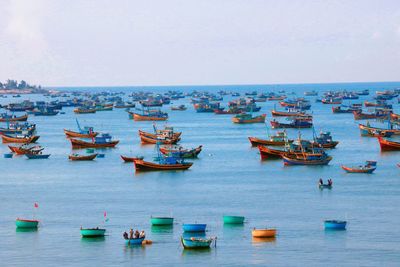 Fishing boats anchored on river against clear sky