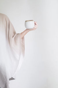 Midsection of woman holding umbrella against white background