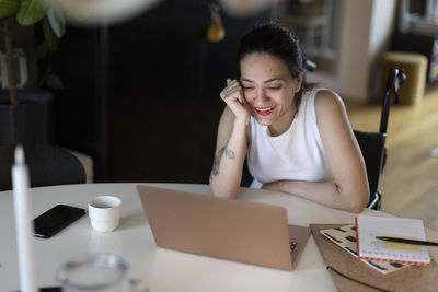 Happy woman with paraplegia enjoying watching laptop at home