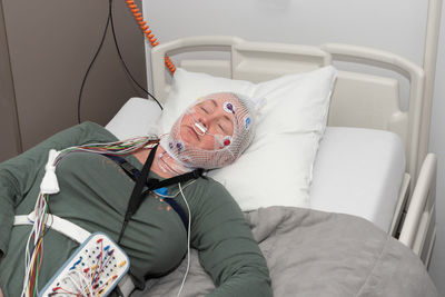 Middle aged woman measuring brain waves, examining polysomnography in sleep lab