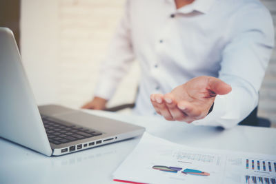 Midsection of man using laptop on table