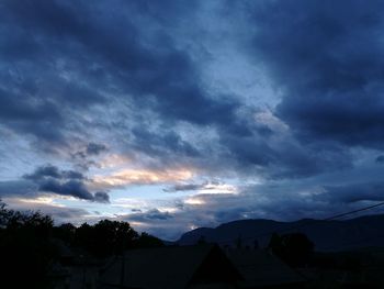 Low angle view of silhouette trees against dramatic sky