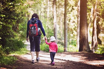 Rear view of mother and daughter in forest