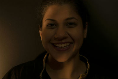 Close-up portrait of a smiling young woman over black background