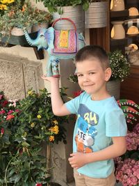Portrait of cute boy touching toy hanging by plants