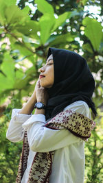 Side view of woman standing against plants