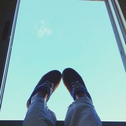 Low section of woman standing against blue sky