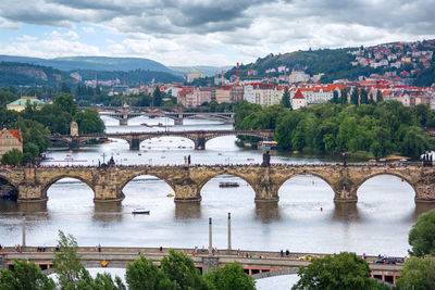 Arch bridge over river in city against sky