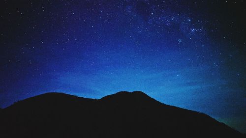 Low angle view of silhouette mountain against sky at night