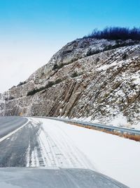 Road by snow covered mountain against sky