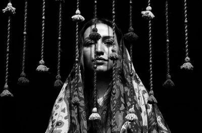 Portrait of woman by wind chime against black background