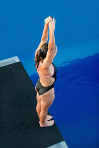 High angle view of mid adult woman standing on diving board over swimming pool
