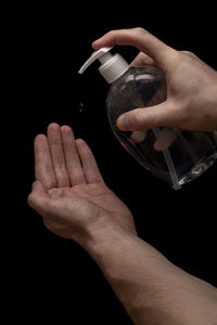 Close-up of hand holding drink against black background