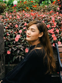 Beautiful woman with closed eyes standing by flowering plants