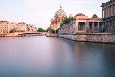 View of building by river against sky in city