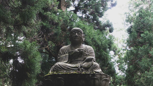 Low angle view of statue against trees in forest