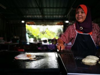 Portrait of young woman standing by food