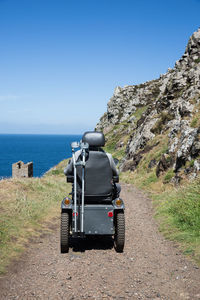 Man on vehicle on dirt road by sea
