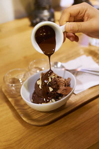 Close-up of hand holding ice cream served on table