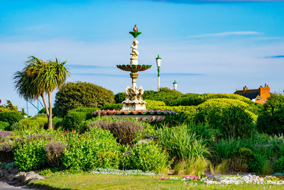 Statue by fountain in garden against sky