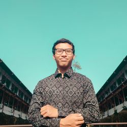 Portrait of young man standing against sky