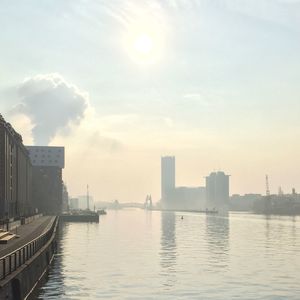 Scenic view of river by city against sky