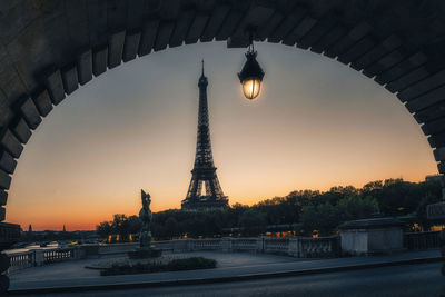 Sunrise in paris with eiffel tower framed by stone arch