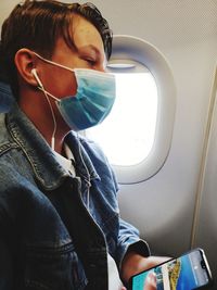 Midsection of man using mobile phone while sitting in airplane