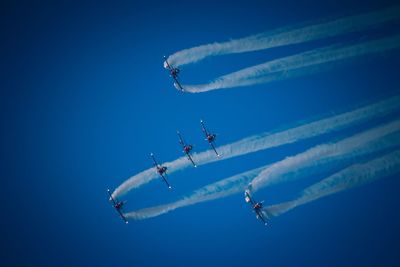 Low angle view of airplanes flying against clear blue sky