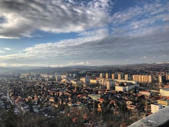 Aerial view of cityscape against cloudy sky