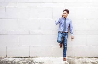 Businessman talking on mobile phone while leaning on wall