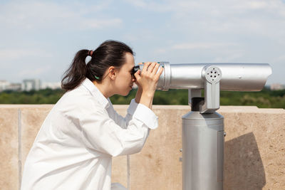 Young man photographing through binoculars