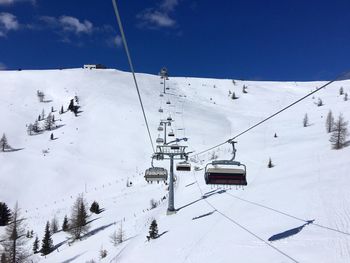 Ski lift over snow covered mountains against sky