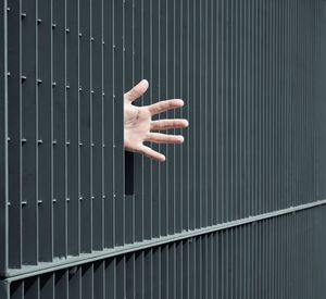 Human hand on metal grate against wall