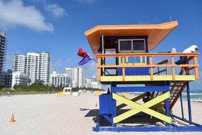 Man standing on lifeguard hut at sandy beach against sky in city