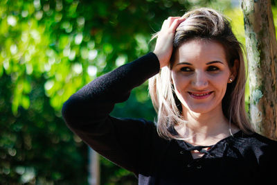 Portrait of smiling young woman against tree