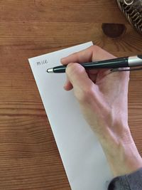 Midsection of man holding paper with text on table