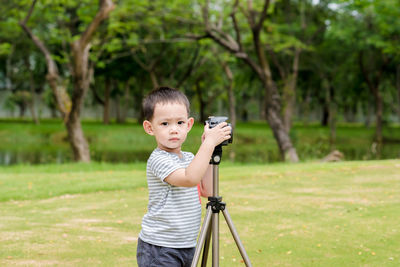 Portrait of cute boy photographing while standing at park